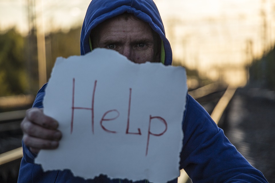 An image of a man holding a sign that says "help"